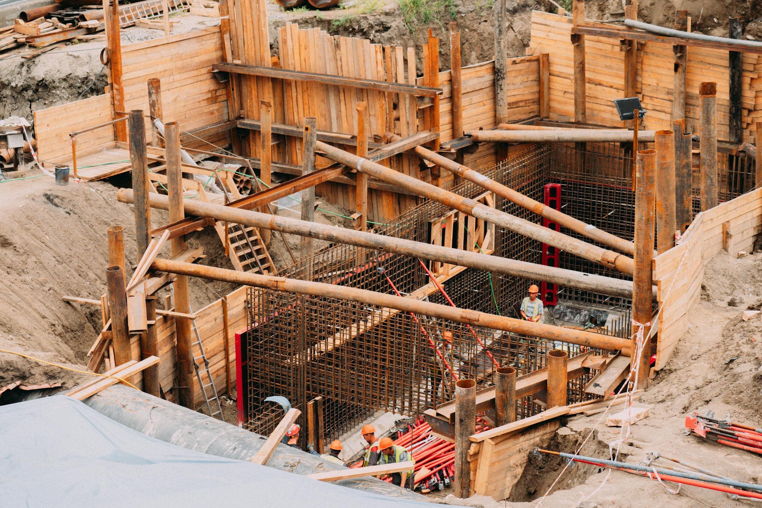 Aerial view of a construction site with workers, wooden framework, and scaffolding.