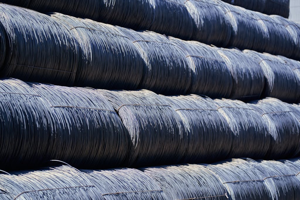 Close-up of stacked industrial steel wire coils glistening in sunlight.