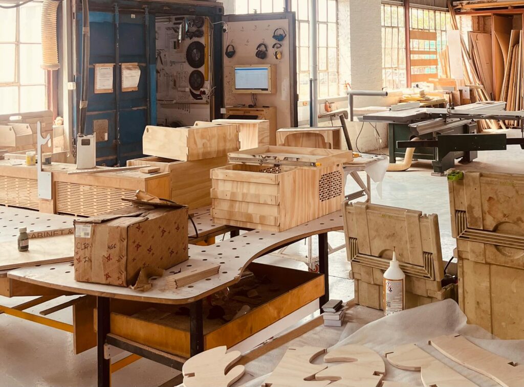 Sunlit workshop filled with wooden craft materials and workbenches in a rustic setting.