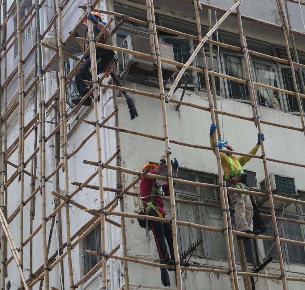 Workers on bamboo scaffolding in Hong Kong building construction, showcasing traditional techniques.